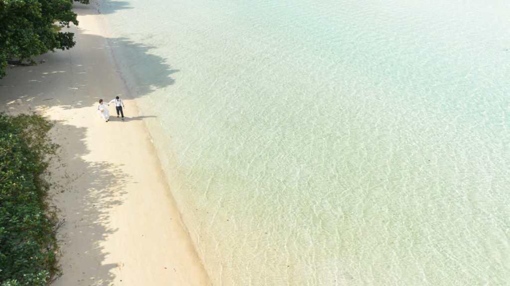 沖縄の海で、楽しく前撮りするカップル